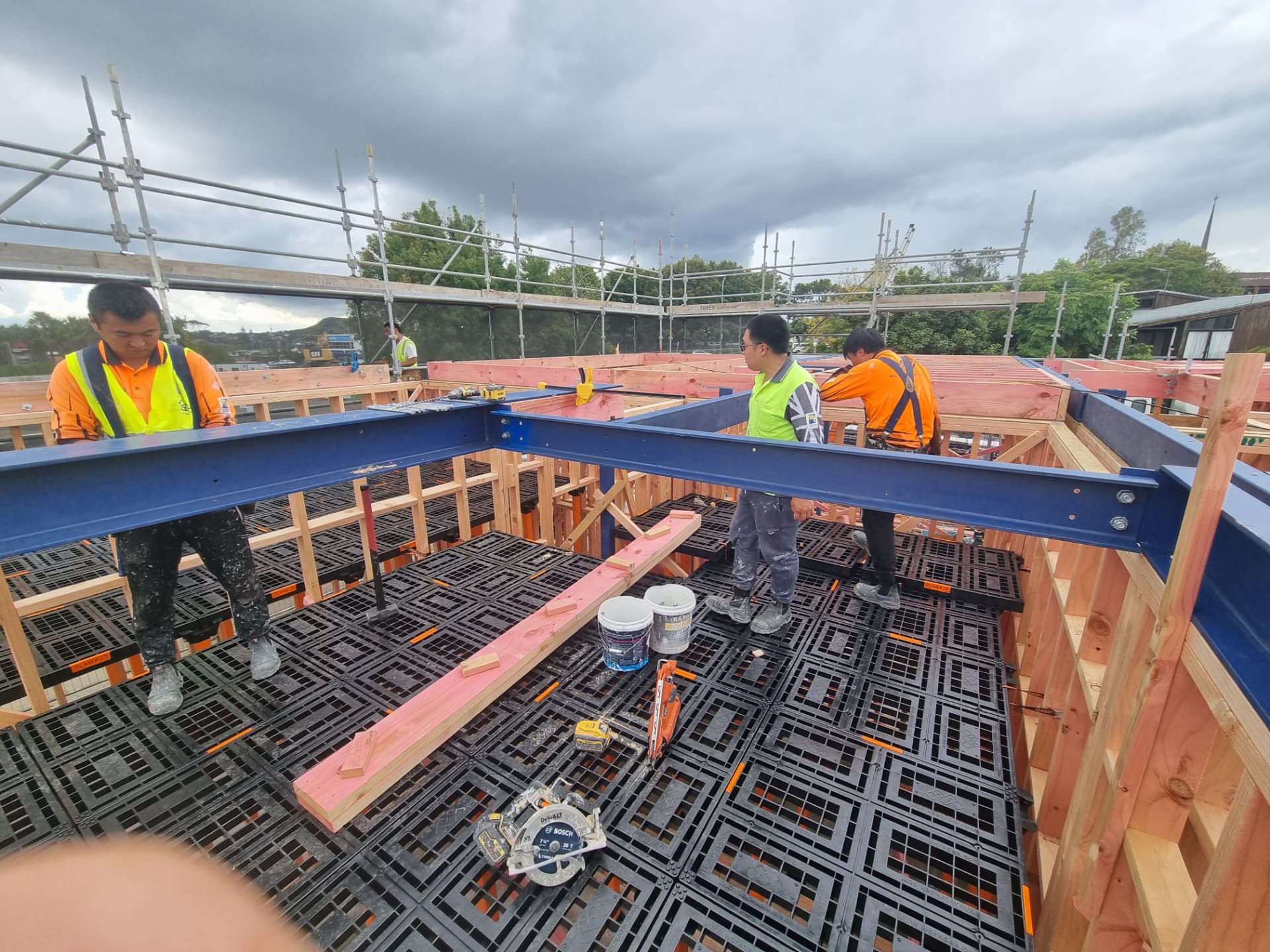 Crew guiding blue structural steel beams into place above a Workdek platform