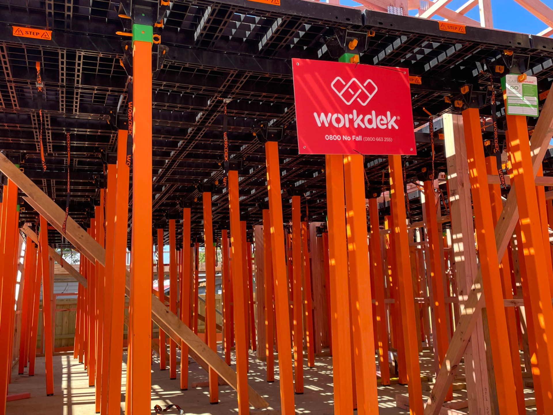 Orange Workdek legs supporting a black deck above a slab, with a Workdek 0800 No Fall site sign
