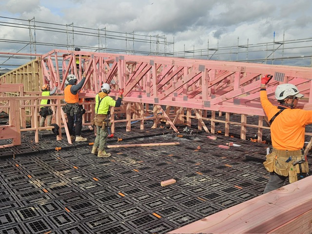 Four builders raising a timber truss while standing on a Workdek platform